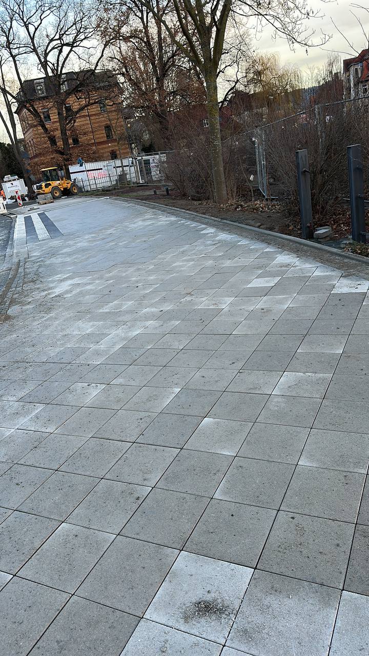 Arbeiter verlegen graue Betonpflastersteine in städtischem Bereich